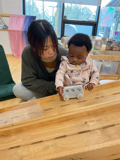 educator and child with car on ramp