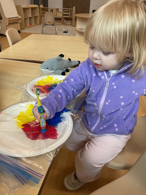 Child in purple mixing colours