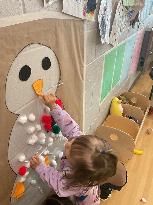 little girl at the cotton ball snowman