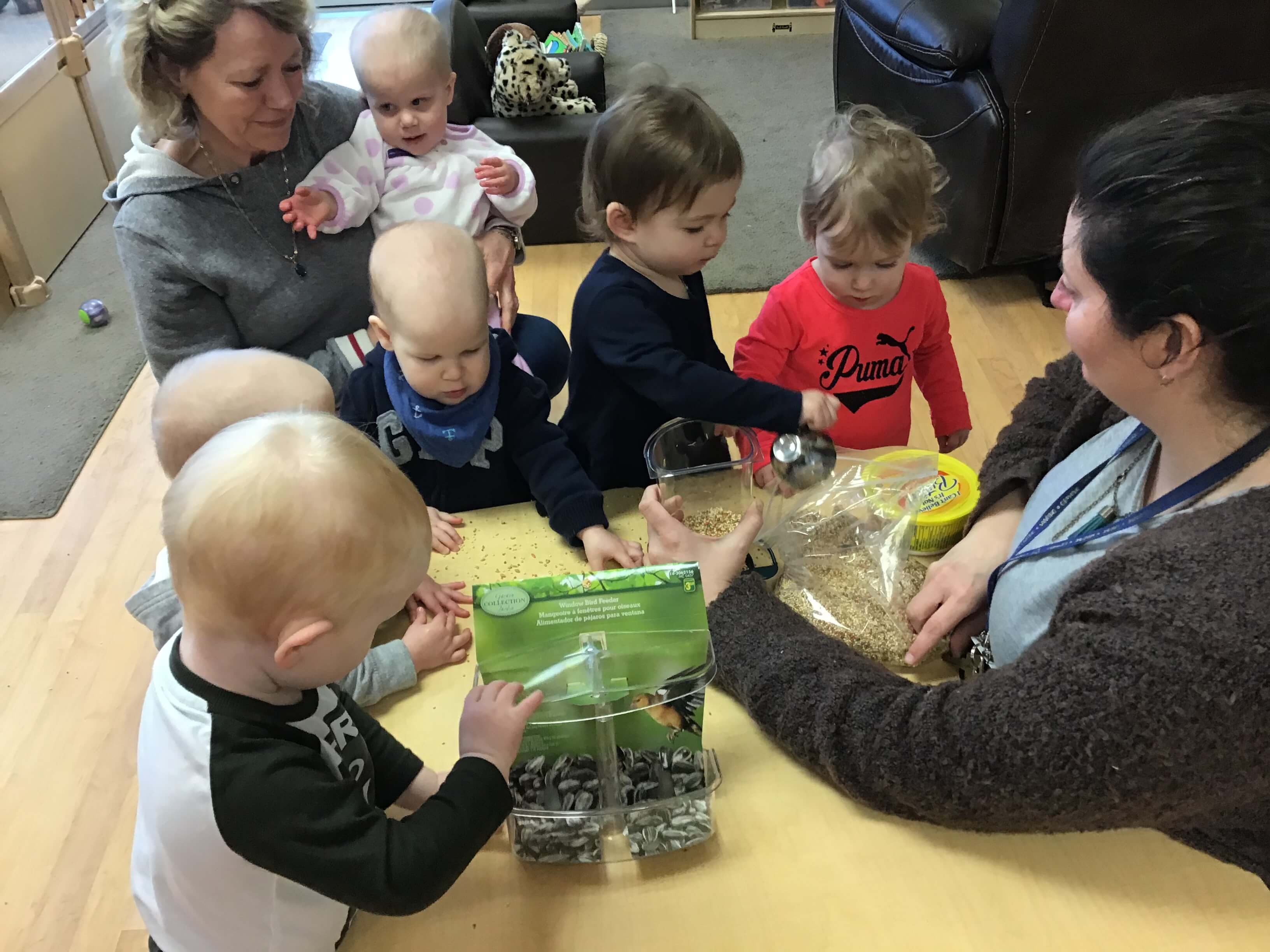 infants putting bird seed in a feeder