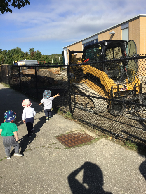 kids pointing at a bulldozer on their playground during construction