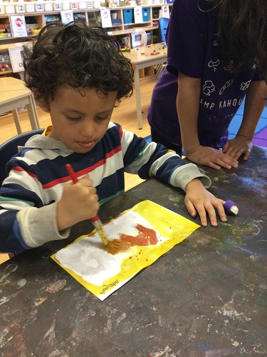 A child painting over the paper to make letters appear