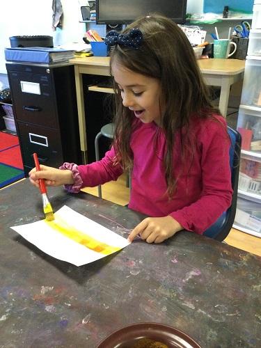 A child looking at letters appearing on her paper