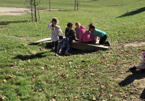 School age group sitting on a little bridge engaged in pretend play