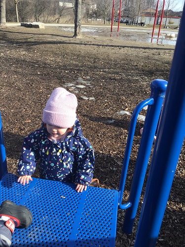 A child climbing up onto a play structure platform
