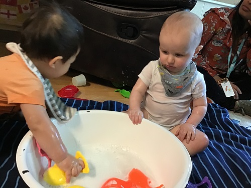 Infants playing with a container of water