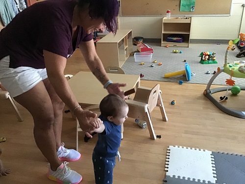 Educator helping an infant walk