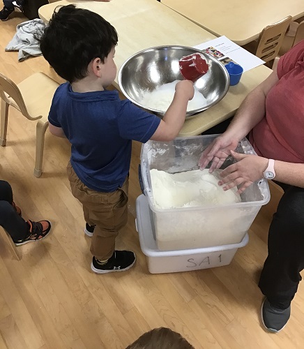 A child scooping ingredients into a bowl