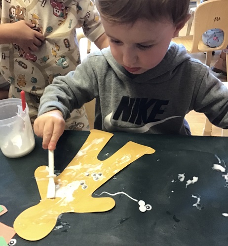 A child adding glue to their paper person