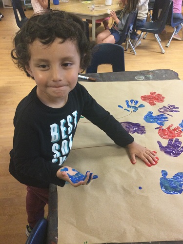 A child adding handprints to paper