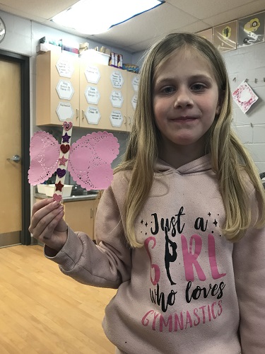 A child holding up the craft they created