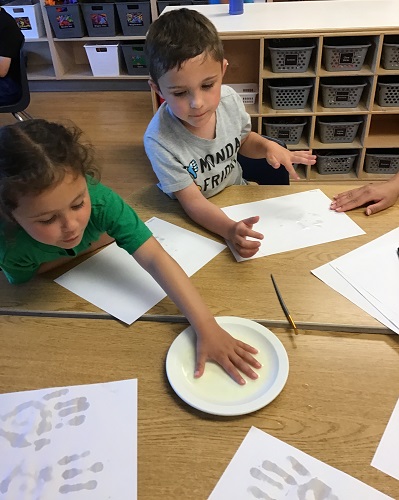 A child dipping their hand into warm water and baking soda