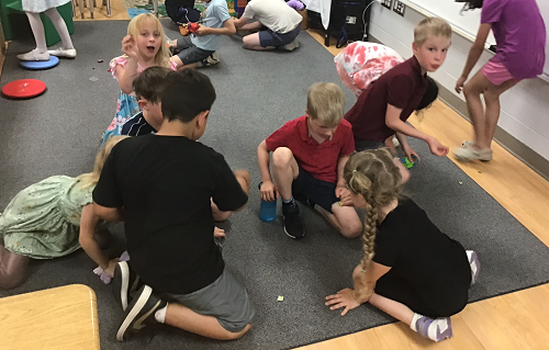 Children crouched on the floor looking for gems