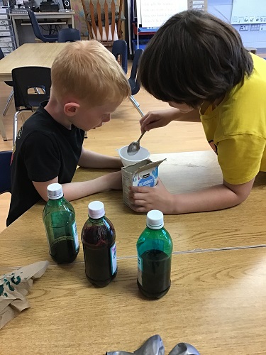 Two children scooping bakingsoda into a funnel