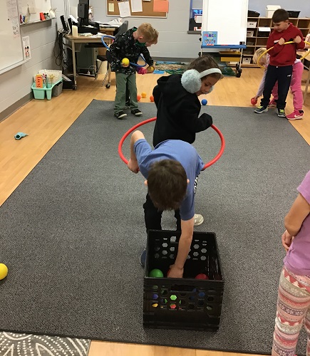 School age children playing a cooperative game, paired inside a hula hoop