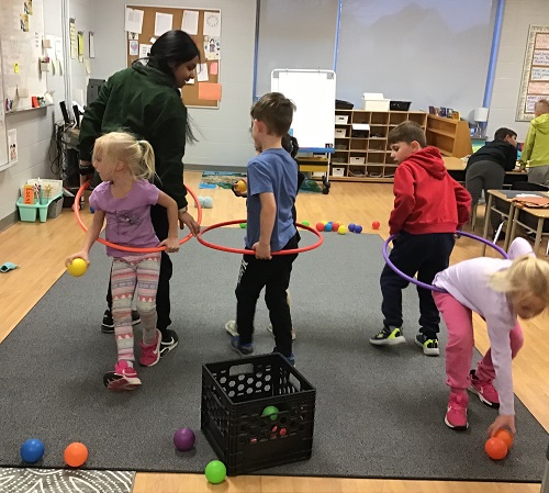 School age children playing a cooperation game, partnered in a hula hoop