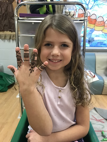 A school aged child showing the Henna designa painted on her hand