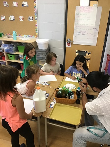 Educator and school aged children exploring with shaving cream and food colour