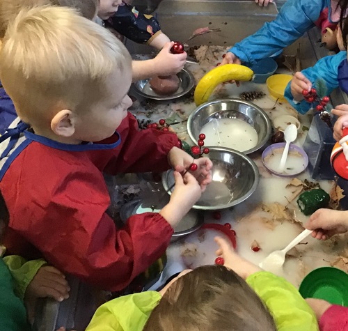 A toddler filling a bowl with items floating in the water