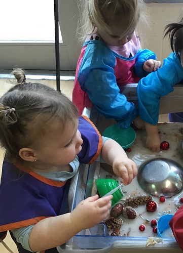 A toddler dumping water out of a bowl
