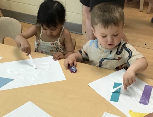 Toddlers gluing on paper