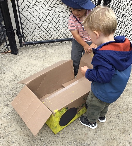 Toddlers looking into the cardboard box bus